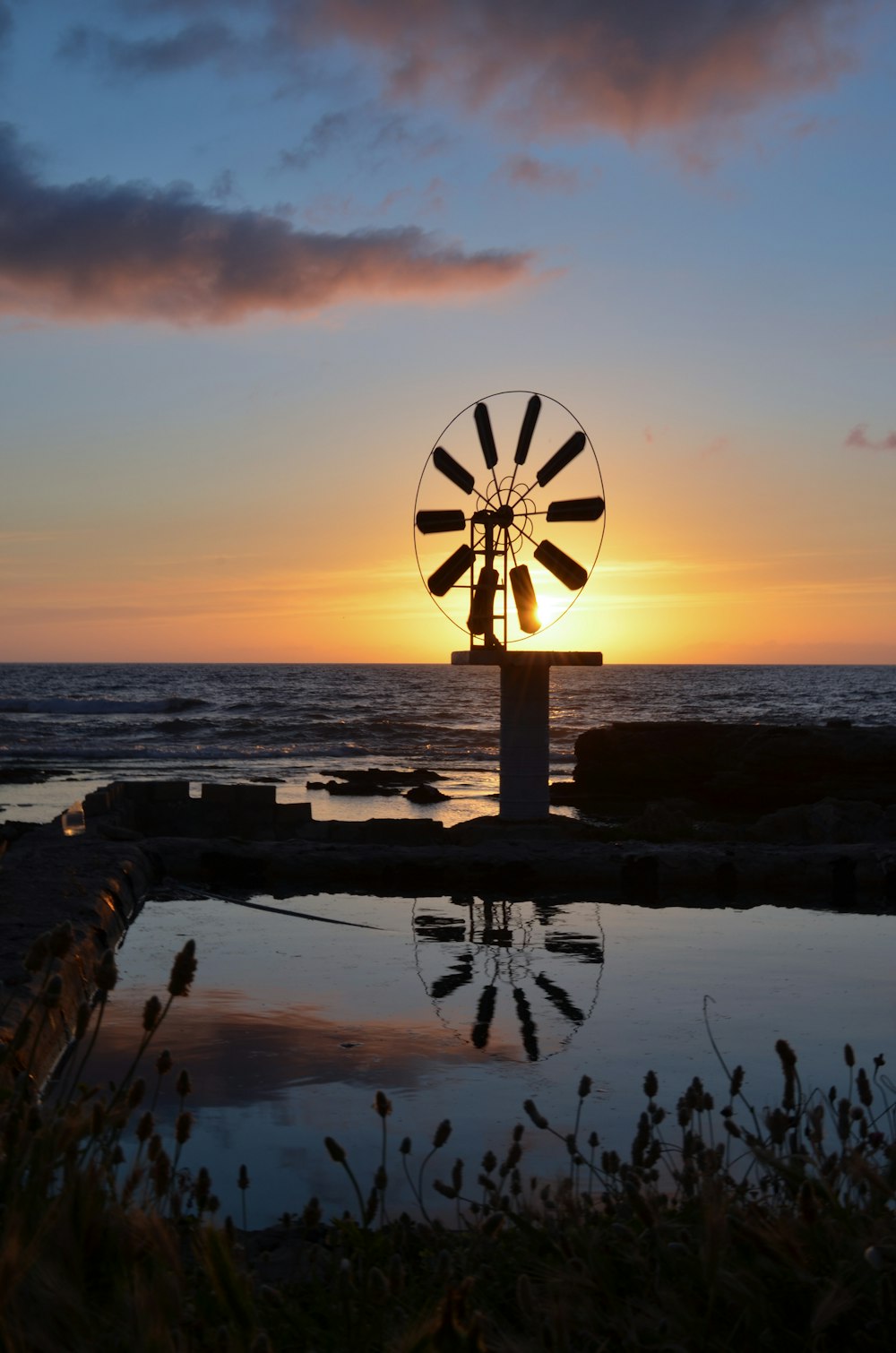 silhouette of windmill near body of water during sunset