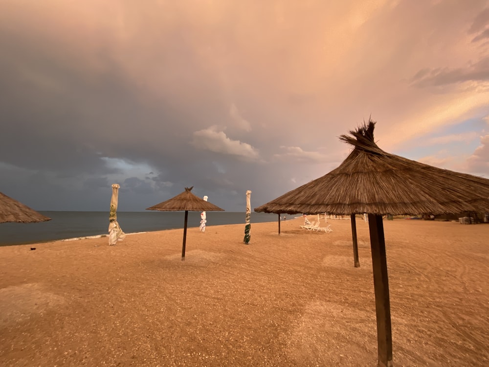 brown wooden beach umbrella on brown sand under gray cloudy sky