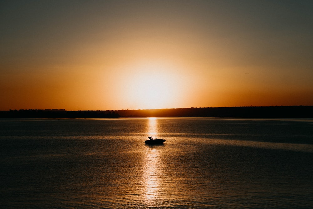 silhouette of boat on sea during sunset