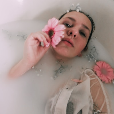 A serene image of a person enjoying a bath with natural soap and flowers around.