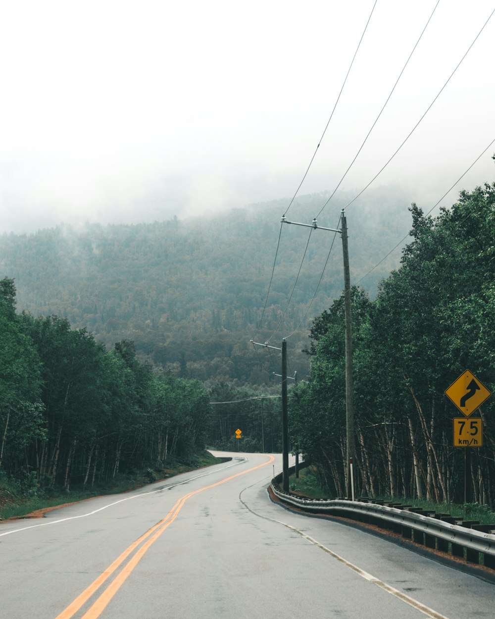 yellow and black road sign on gray asphalt road during daytime