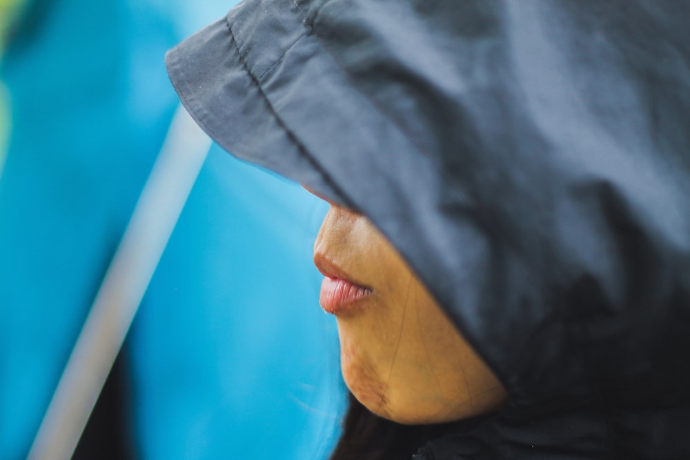woman in black hijab covering her face with blue textile
