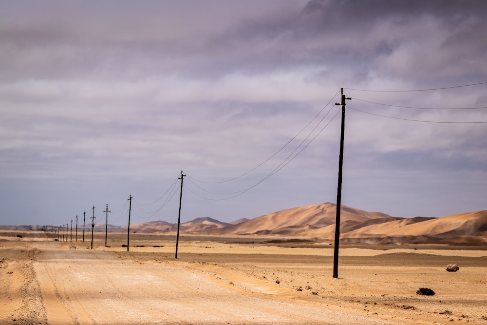 brown wooden electric post on brown sand under white cloudy sky during daytime