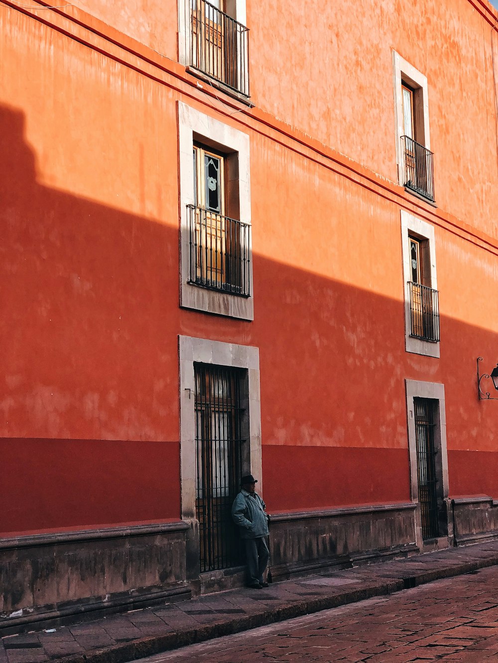 man in black jacket standing beside brown concrete building during daytime