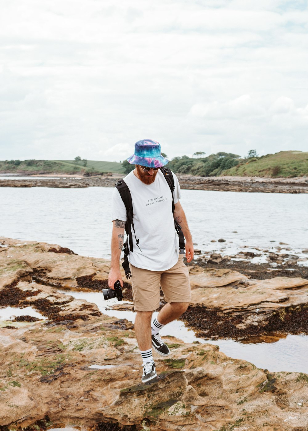 a man with a backpack and a camera on a rocky shore