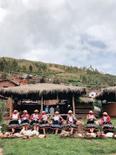 A group of indigenous women teaching children traditional Andean crafts outdoors.