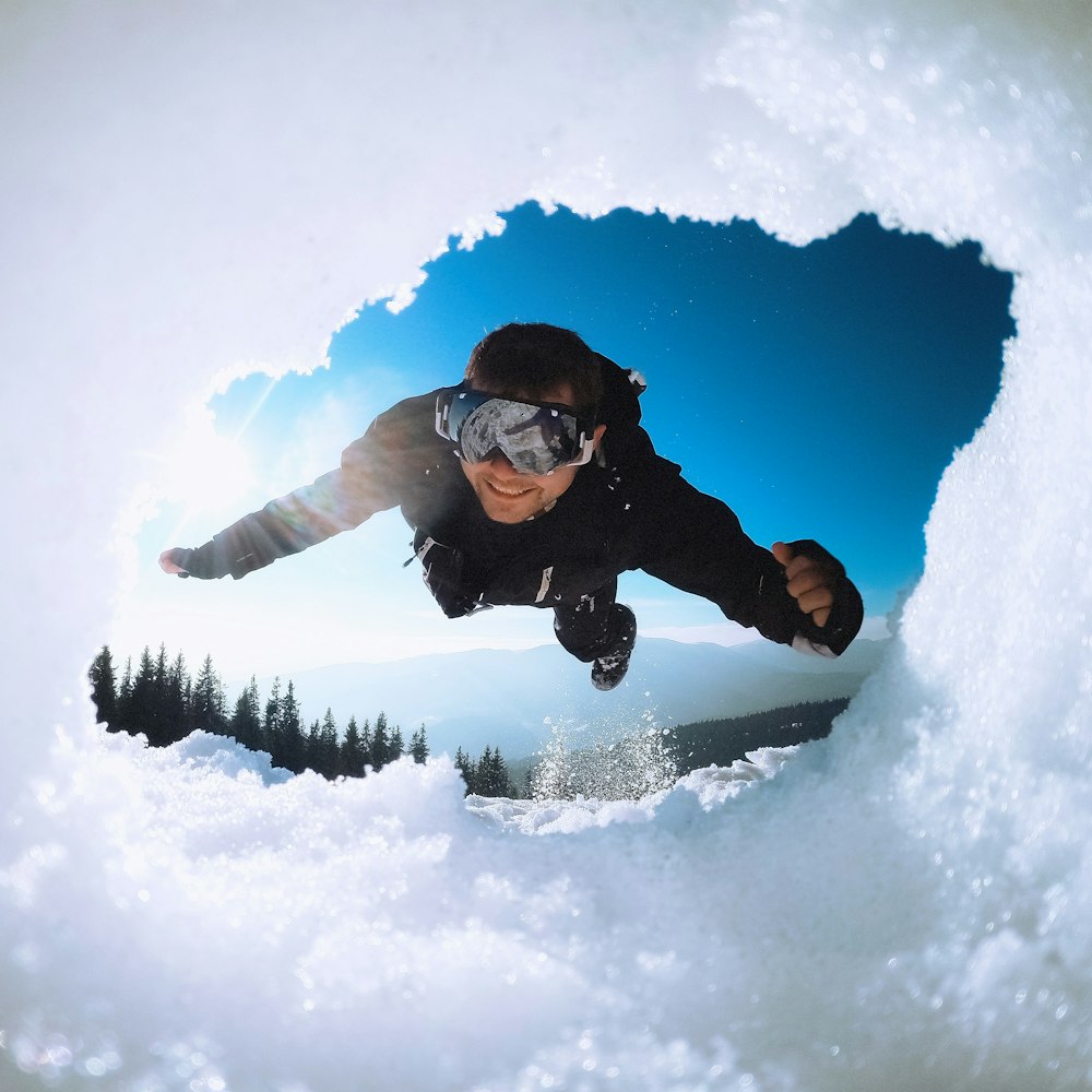 man in black jacket and blue denim jeans on snow covered ground during daytime