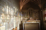 A peaceful chapel interior with stained glass casting colorful light on a simple wooden altar.