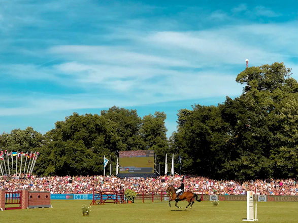 A vibrant photo capturing riders and horses competing in a lively equestrian event under clear skies.