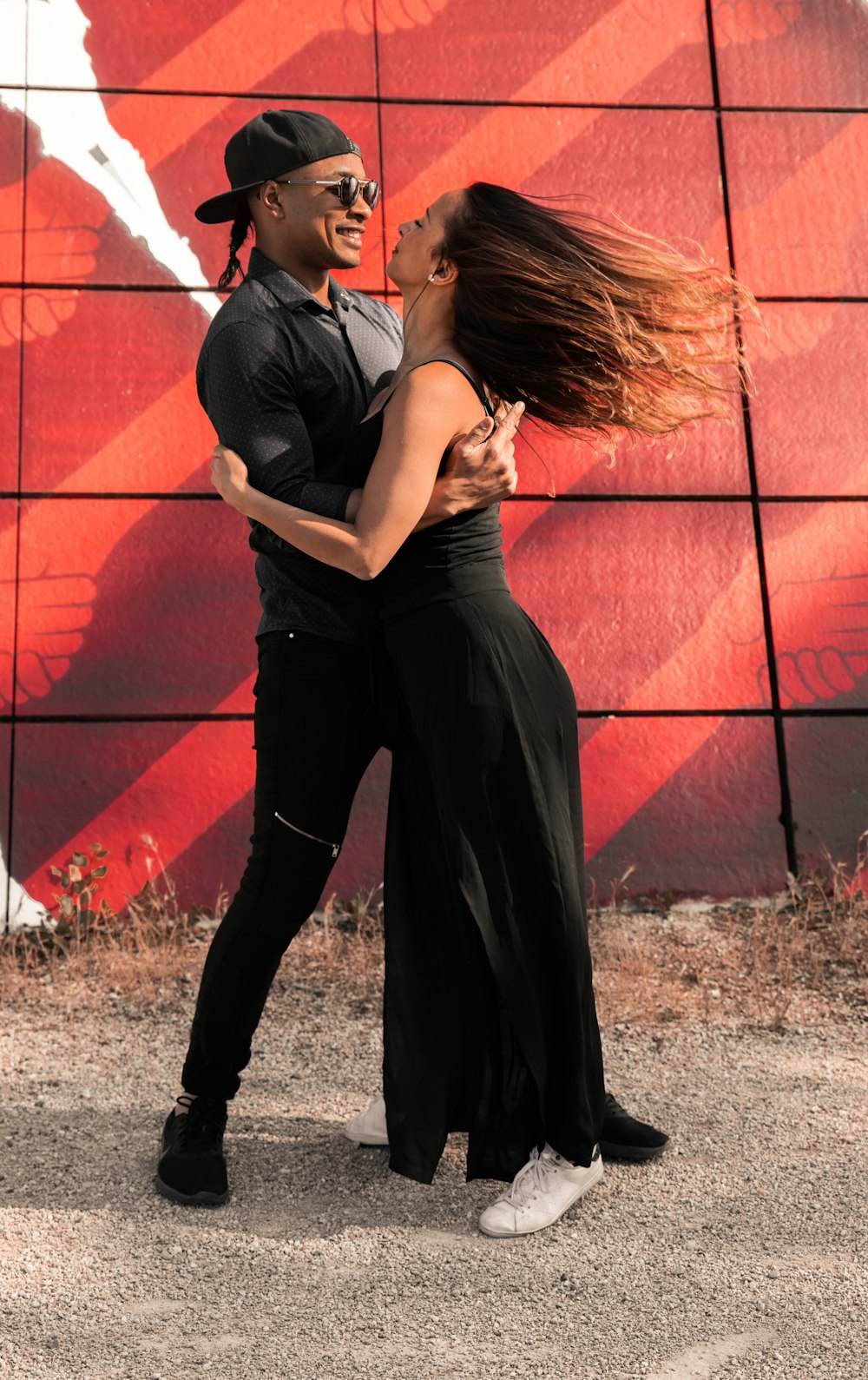 woman in black tank top and black pants leaning on red brick wall during daytime