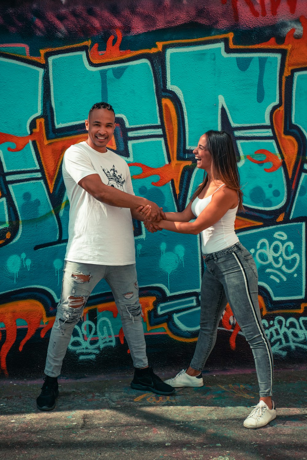 man in white crew neck t-shirt and blue denim jeans standing beside woman in white