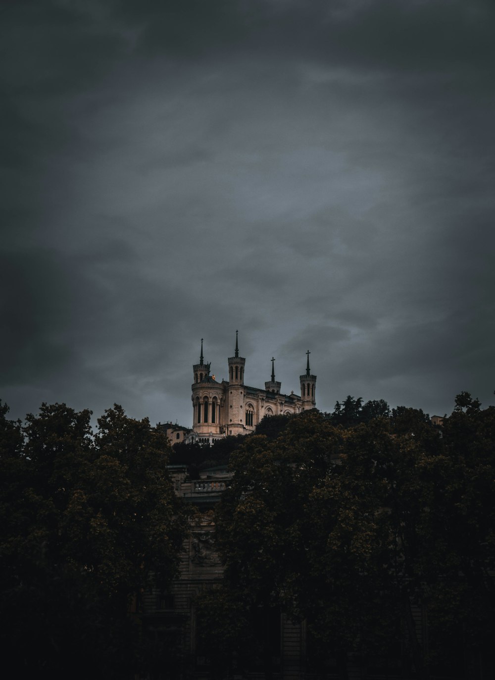 brown concrete building surrounded by trees under gray clouds