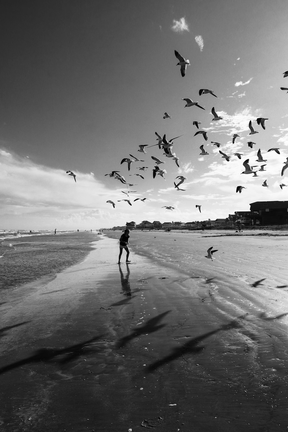 grayscale photo of woman walking on beach