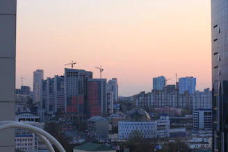 A panoramic cityscape showcasing a modern mixed-use development under construction at dusk.