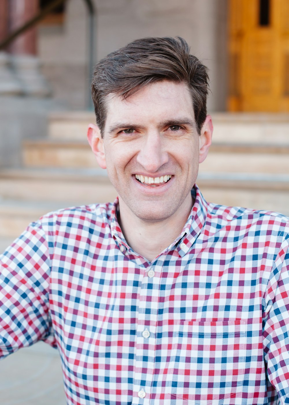 man in red blue and white plaid dress shirt smiling