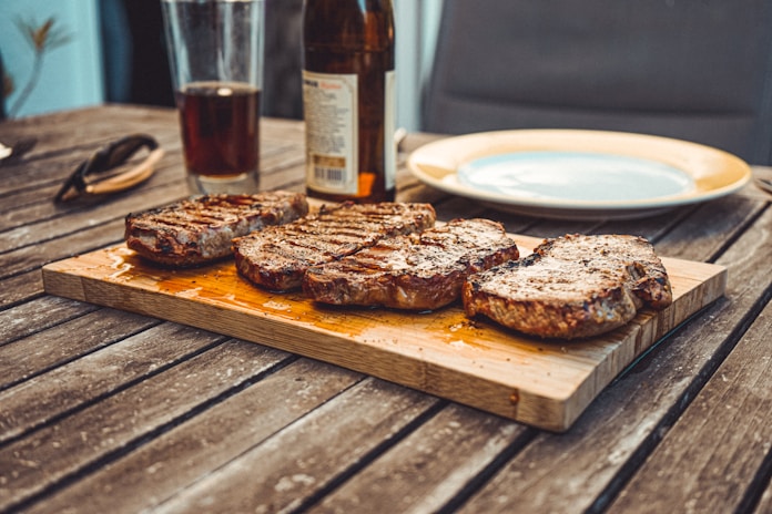 Strip steaks on brown wooden board
