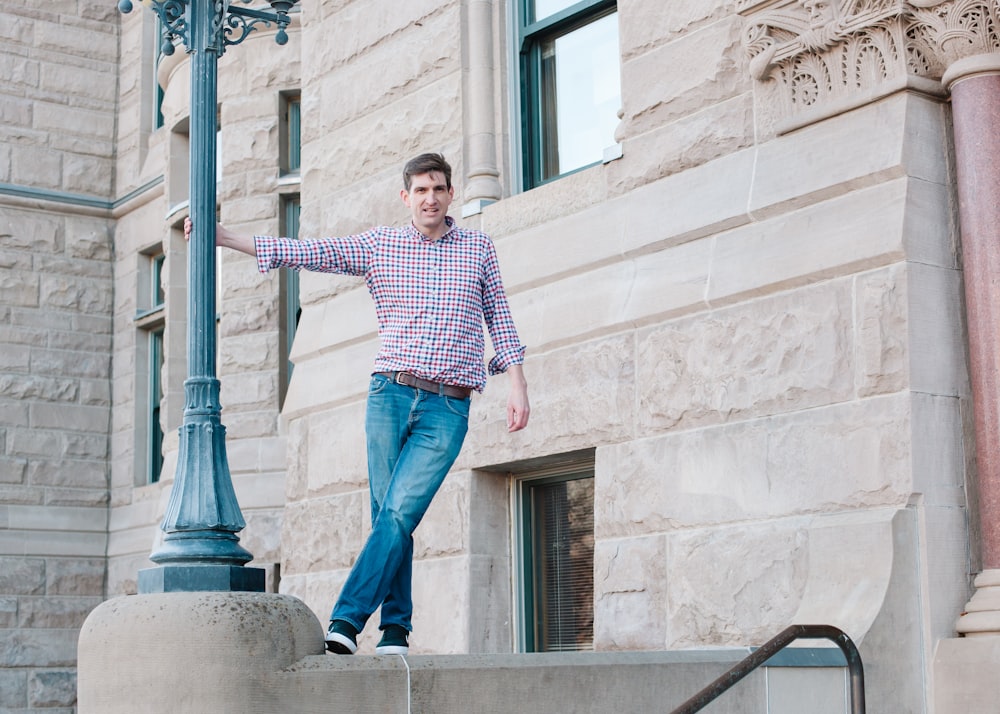 man in blue and white striped long sleeve shirt and blue denim jeans standing on gray