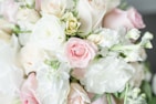 Close-up of a delicate floral arrangement with roses, lilies, and greenery in soft focus