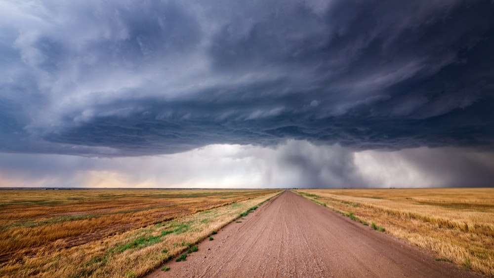 brown dirt road under gray clouds