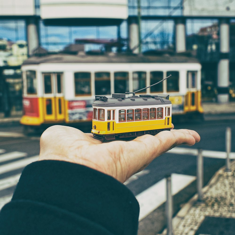 person holding yellow and white train toy