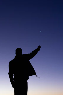 A dramatic silhouette of Raphael standing against a full moon, cape flowing in the wind.