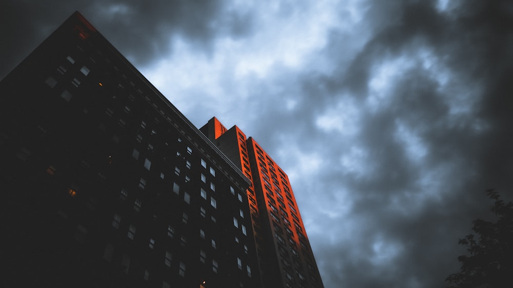 red and black high rise building under gray clouds
