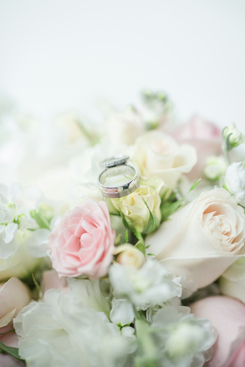 anel de prata no buquê de rosas brancas e cor-de-rosa