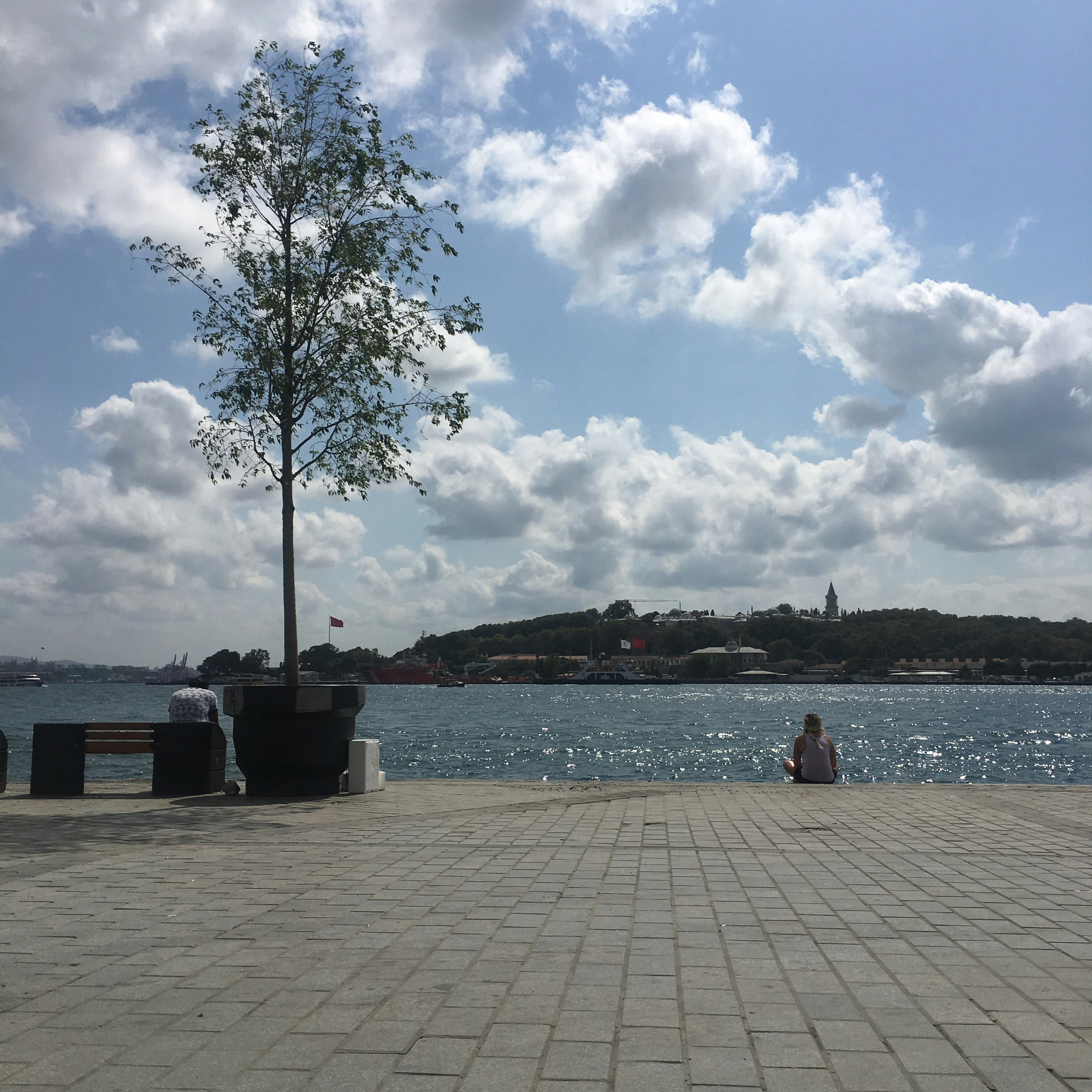 Person sitting on bench near body of water during daytime