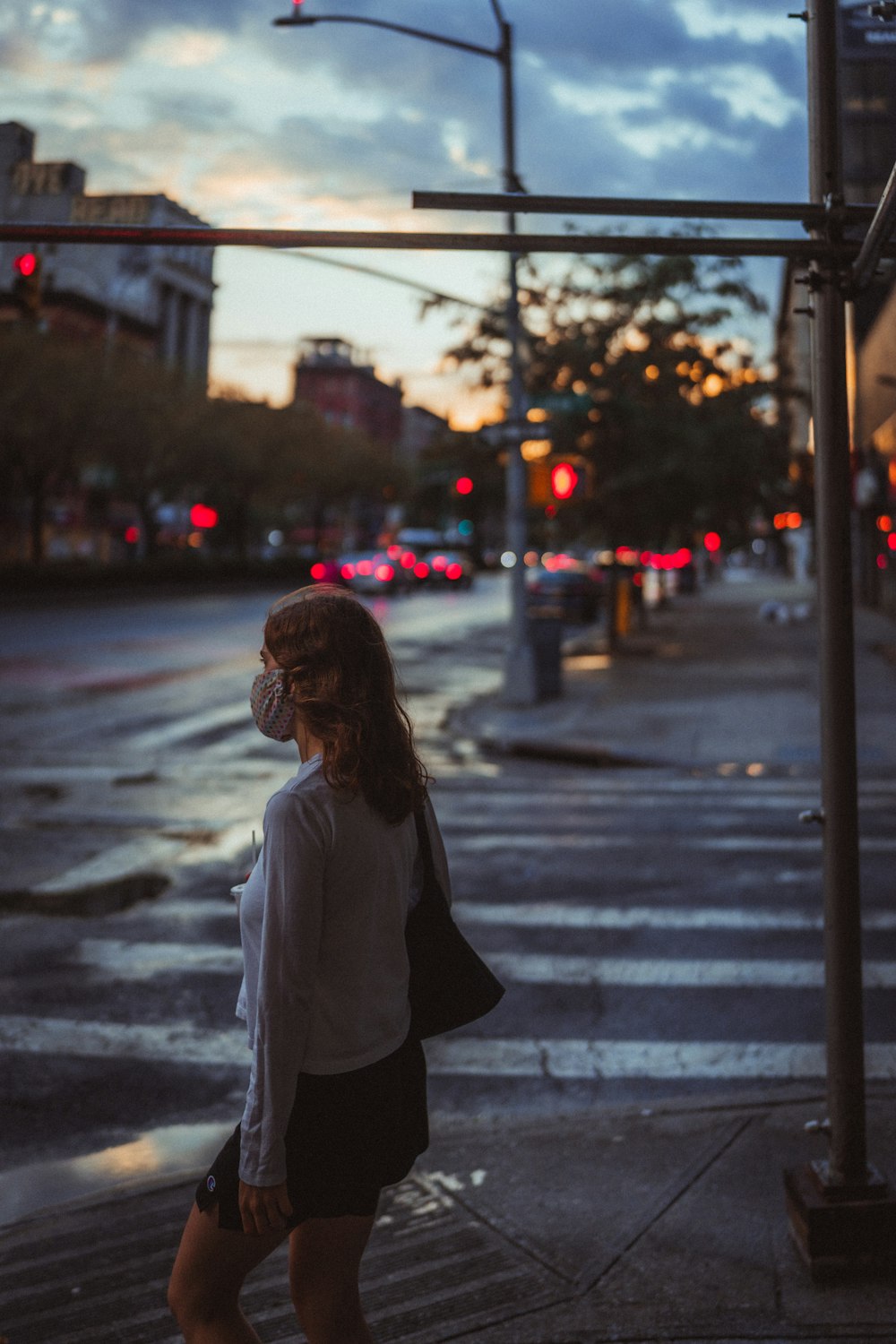 woman in white shirt and black pants standing on pedestrian lane during night time