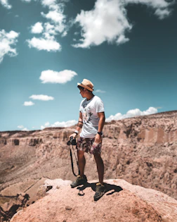 man in white t-shirt and black shorts riding bicycle on brown rock mountain during daytime