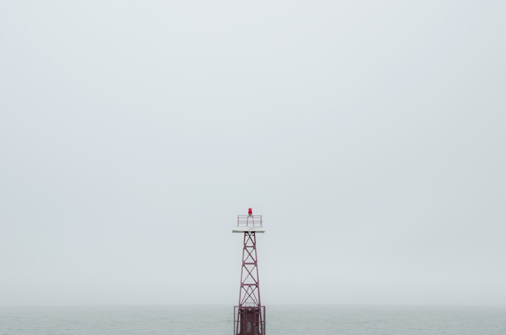 red and white tower on the sea