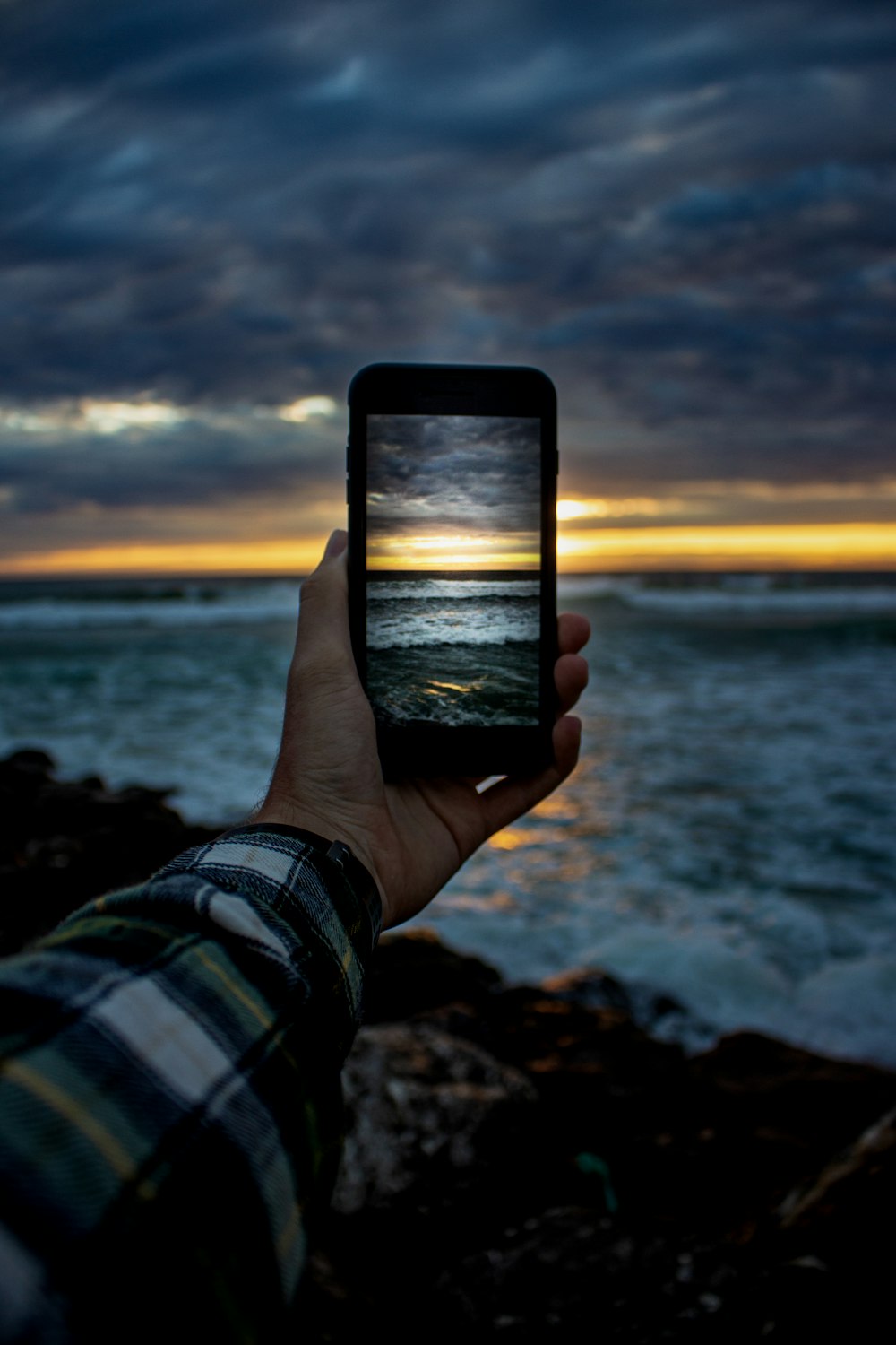 person holding black smartphone taking photo of sea during sunset
