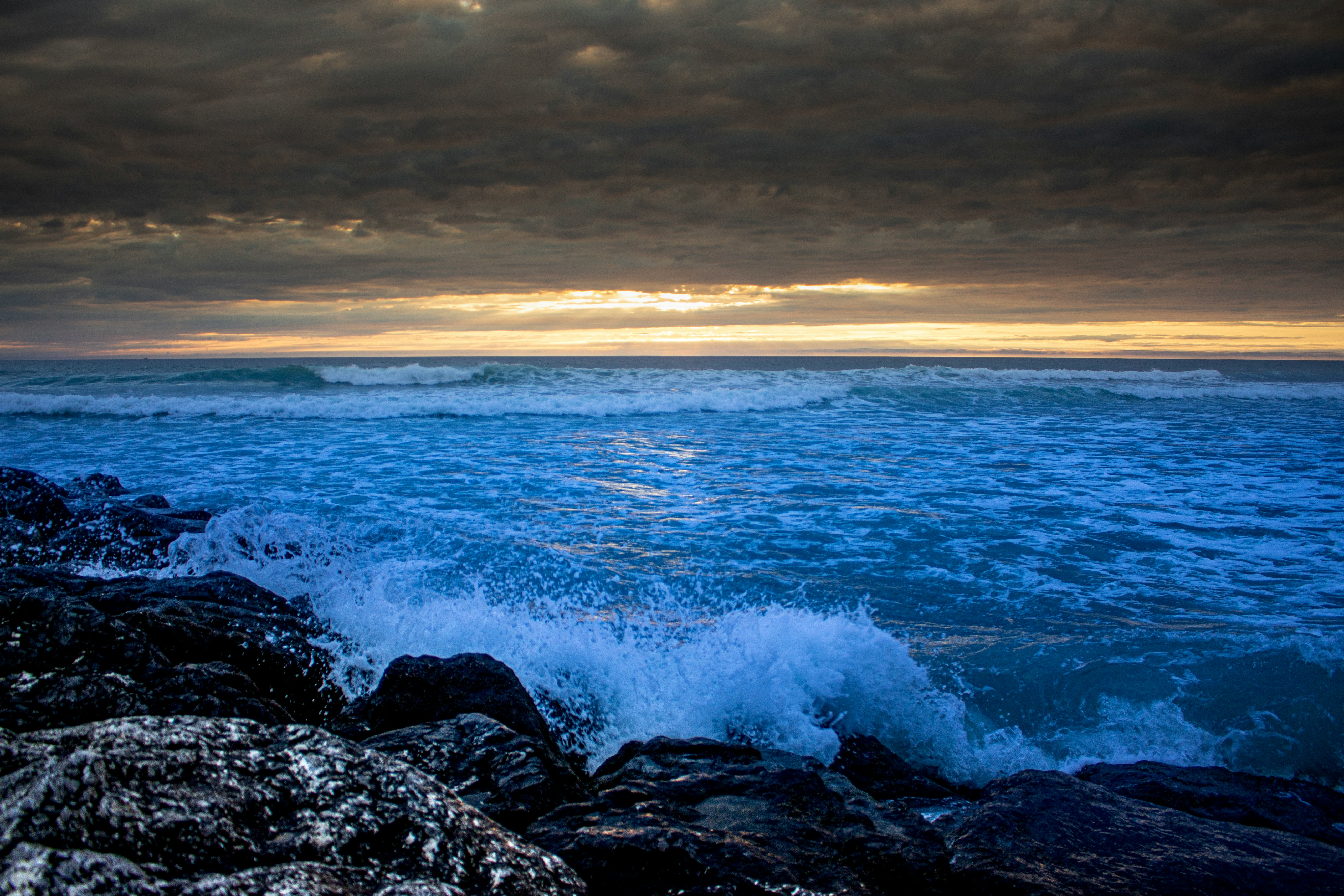 ocean waves crashing on rocks during sunset