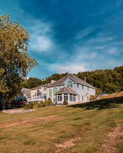 Modern white house with large glass windows and a green lawn under a clear blue sky.
