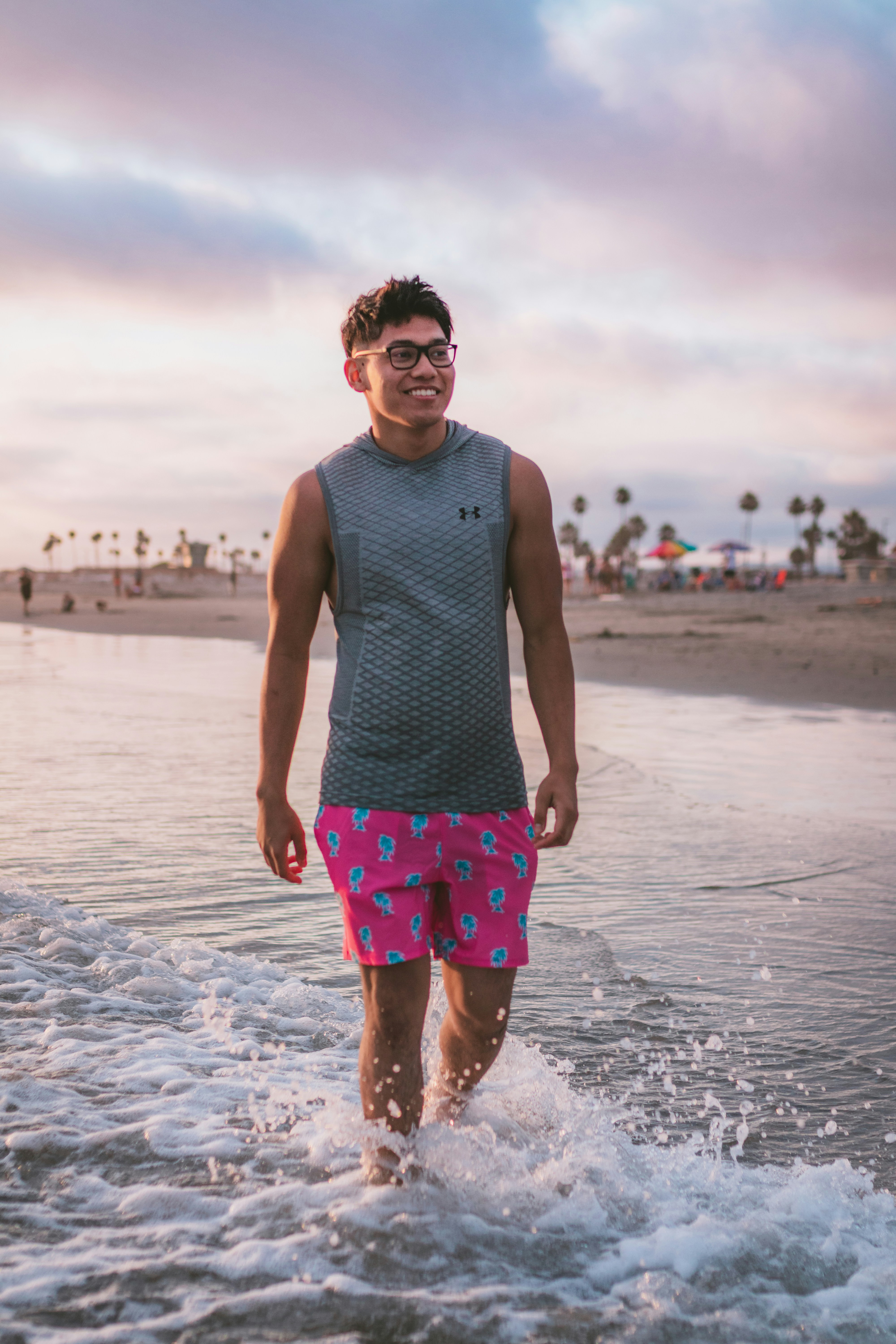 man in black tank top and green and red shorts standing on beach during daytime