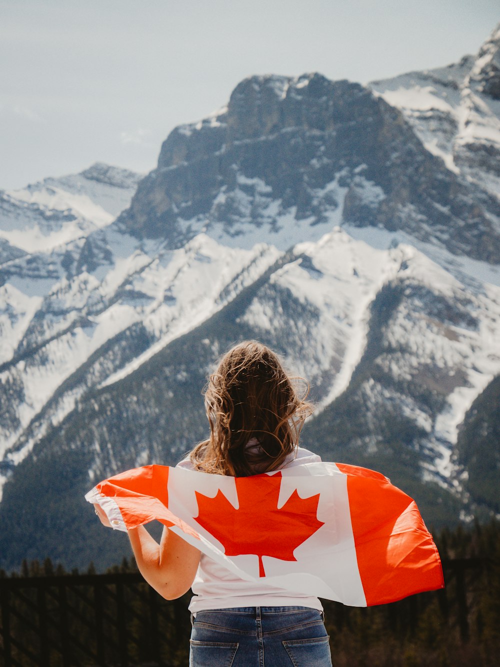 Mujer con camisa naranja y blanca mirando las montañas cubiertas de nieve durante el día