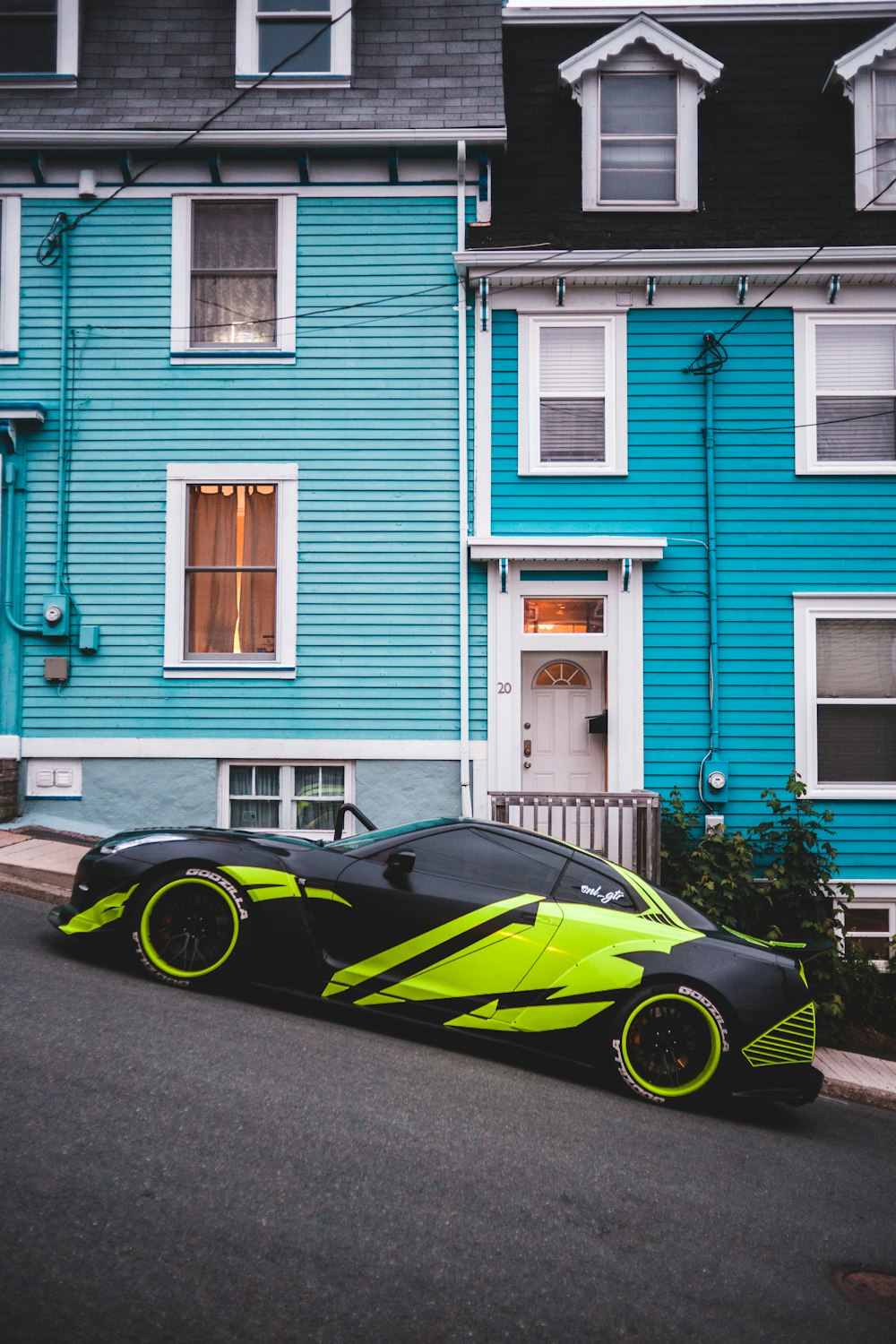 black and yellow ferrari coupe parked beside blue and white wooden house during daytime