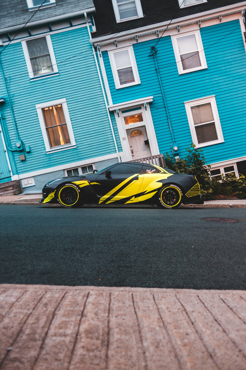 black and yellow lamborghini aventador parked beside blue and white house