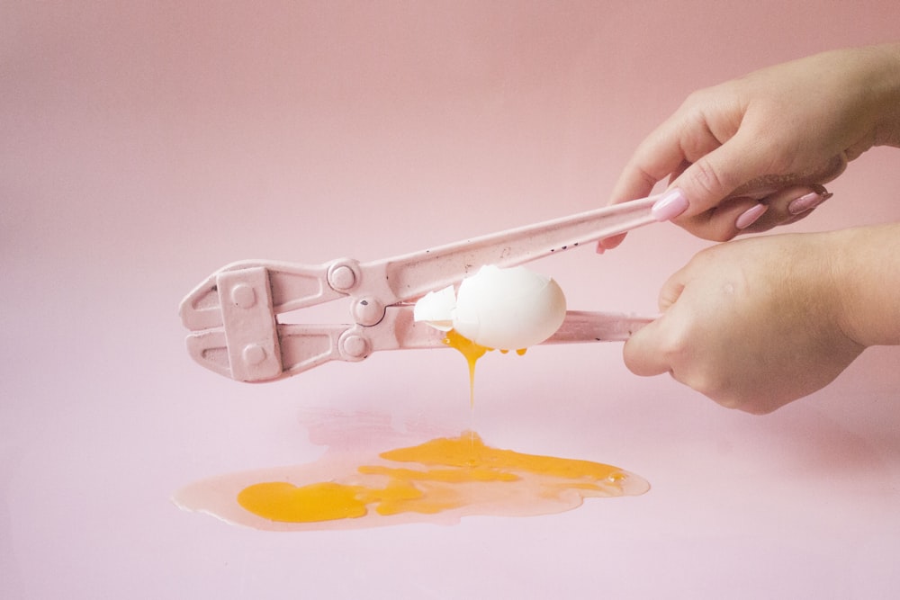 person holding white plastic spoon with yellow powder