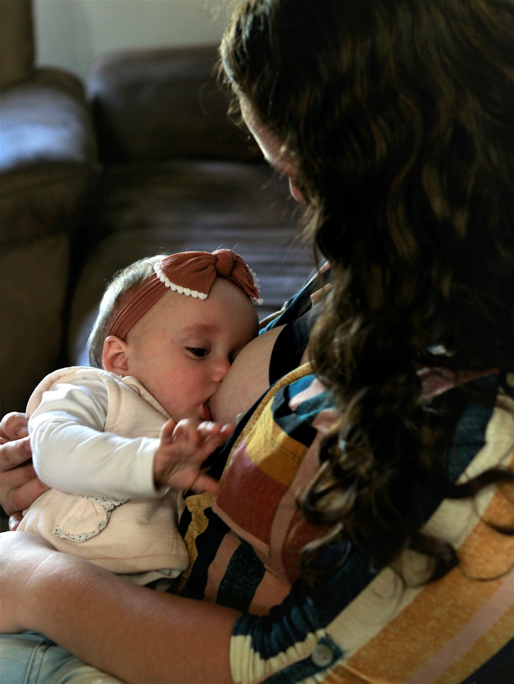 woman in black jacket carrying baby in white onesie