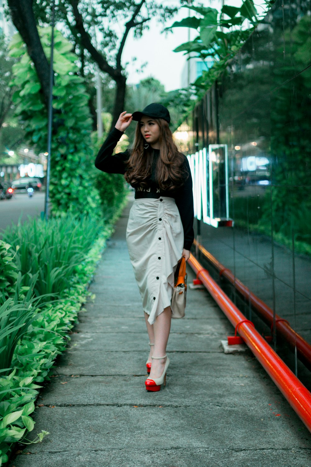 woman in black long sleeve shirt and white skirt standing on train rail during daytime