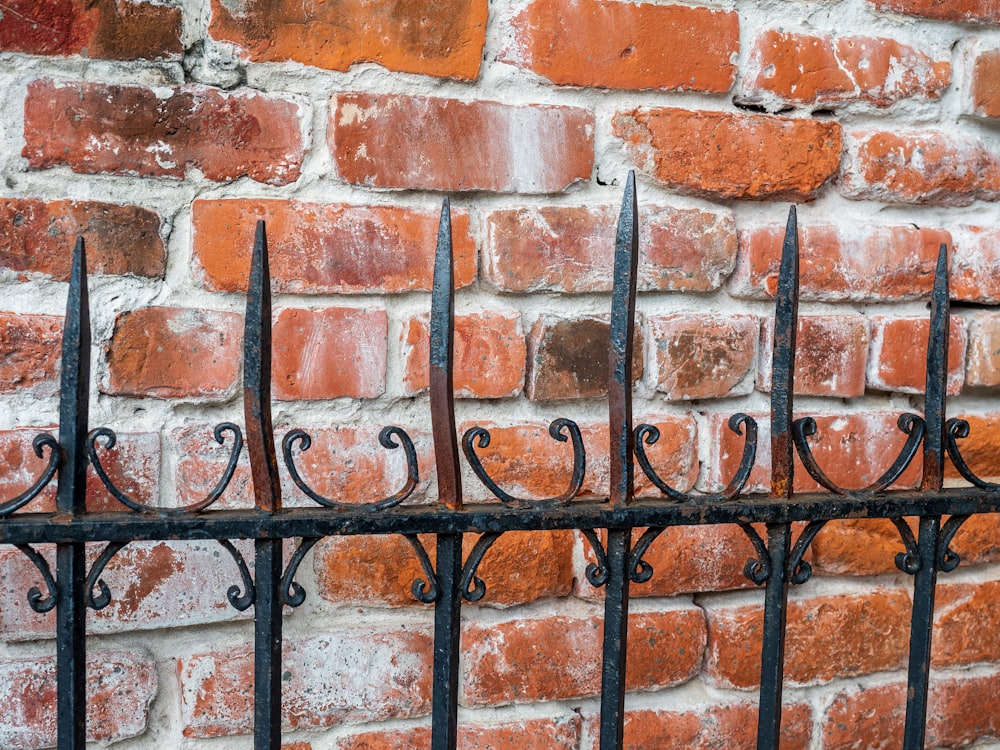 black metal fence on brown brick wall