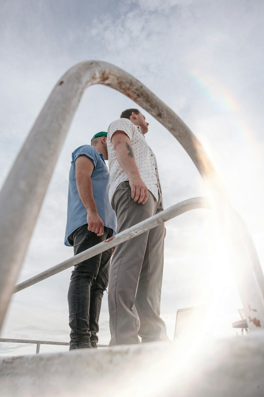 man in blue denim jacket and blue denim jeans standing on white concrete bridge during daytime