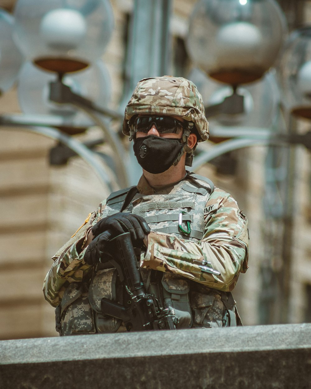 uomo in uniforme mimetica marrone e nera che tiene il fucile