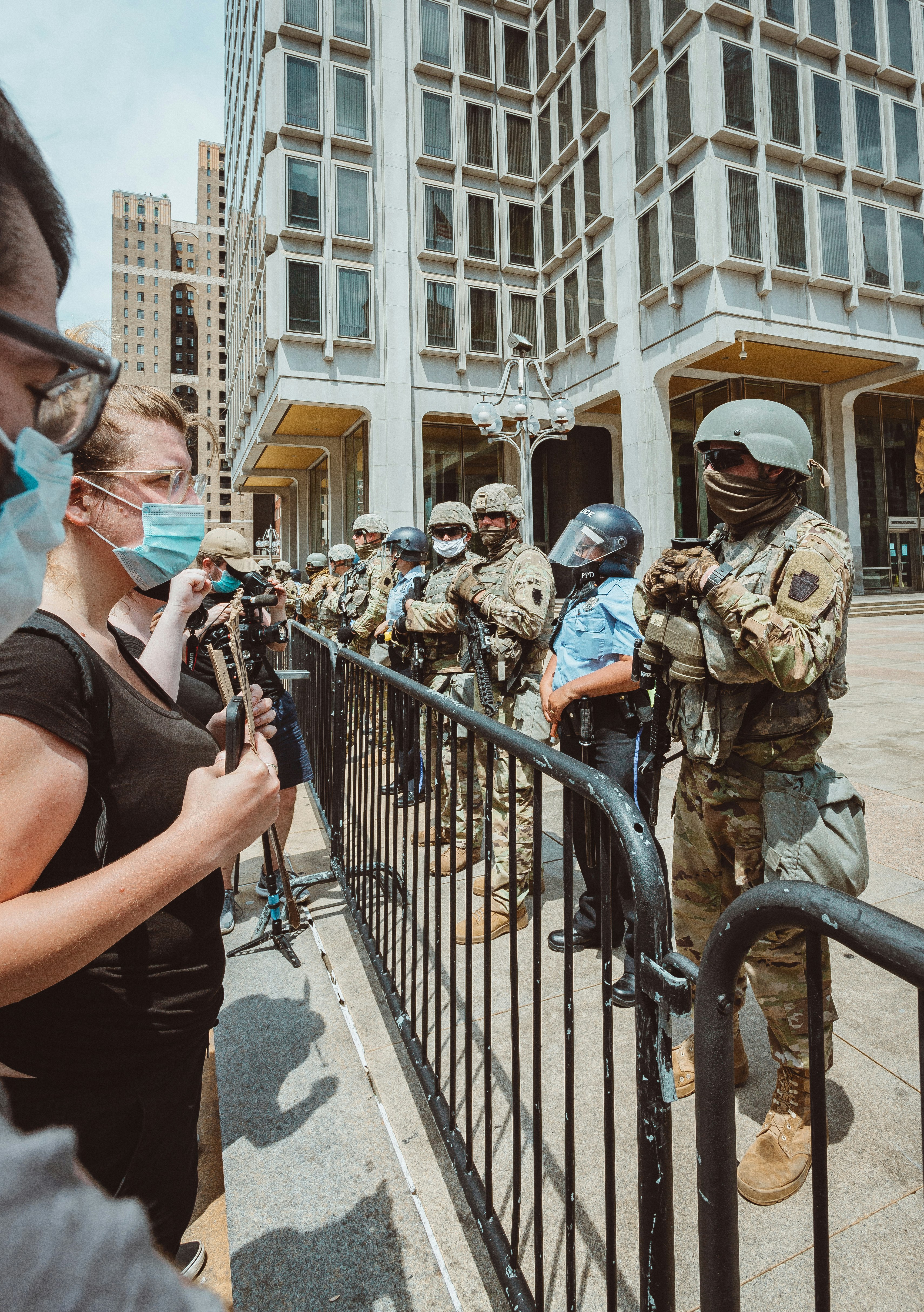 man in black tank top and brown camouflage backpack holding black dslr camera