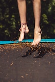 Close-up of feet bouncing on a mini rebounder with coral and teal accents in the background.