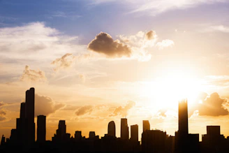 A vibrant Philadelphia skyline at sunset with warm golden light reflecting off the buildings.