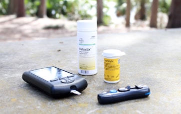 black smartphone beside white plastic bottle and black smartphone