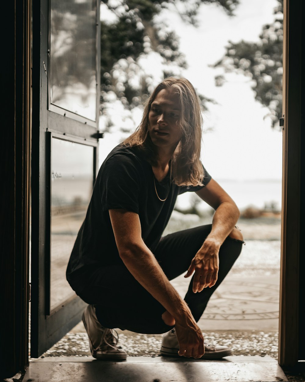 woman in black t-shirt and gray pants sitting on window during daytime