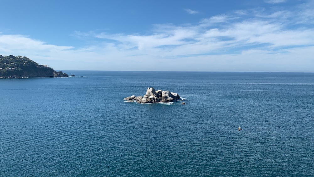 gray rock formation on blue sea under blue sky during daytime